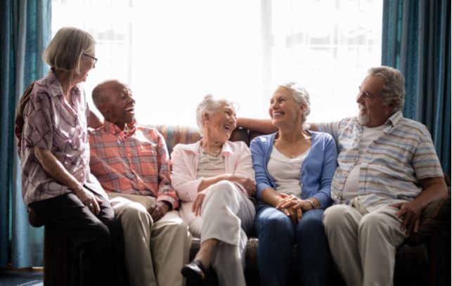 Happy seniors sitting on couch and socializing with one another