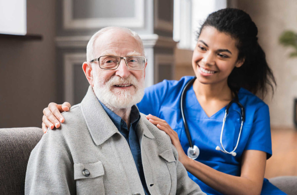 A smiling young female nurse checks up on a senior man.