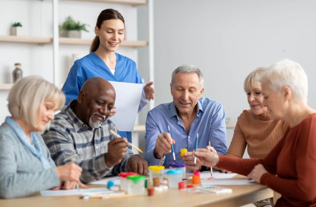 A group of friends in memory care participating in art therapy by painting.