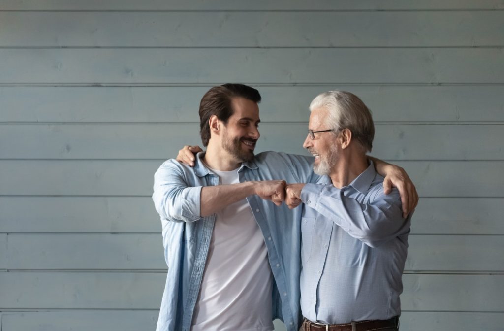 A younger adult and a senior touching their fists together in celebration of mutual understanding and smiling together.