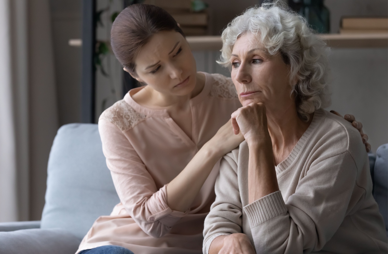 A woman supporting a senior loved one, showing signs of caregiver exhaustion and stress.