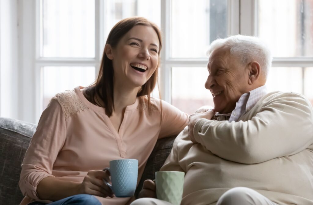 Adult daughter and her senior parent laughing together in a memory care community.