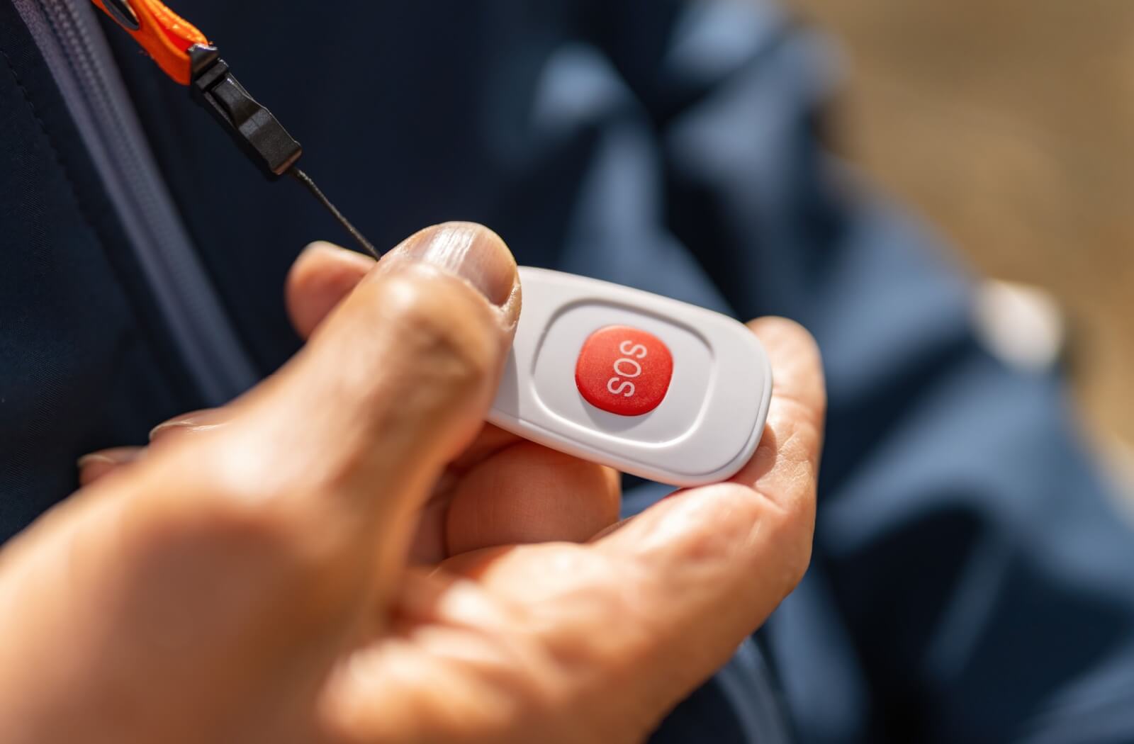 Close-up view of a senior holding a personal alert button lanyard clipped around their neck to use for emergencies